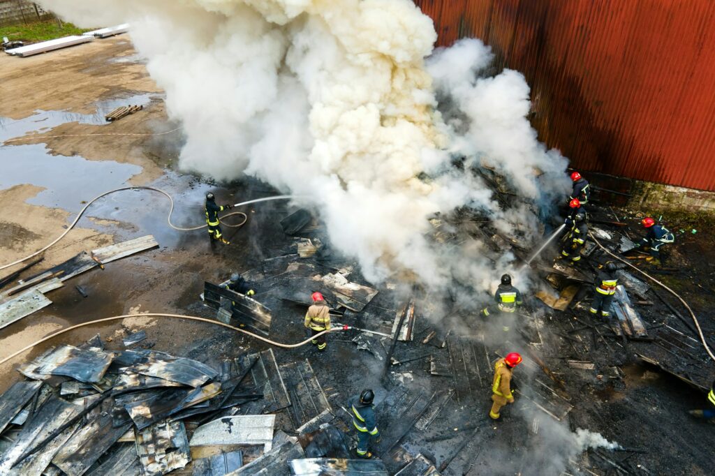 Aerial view of firefighters extinguishing fire in industrial area