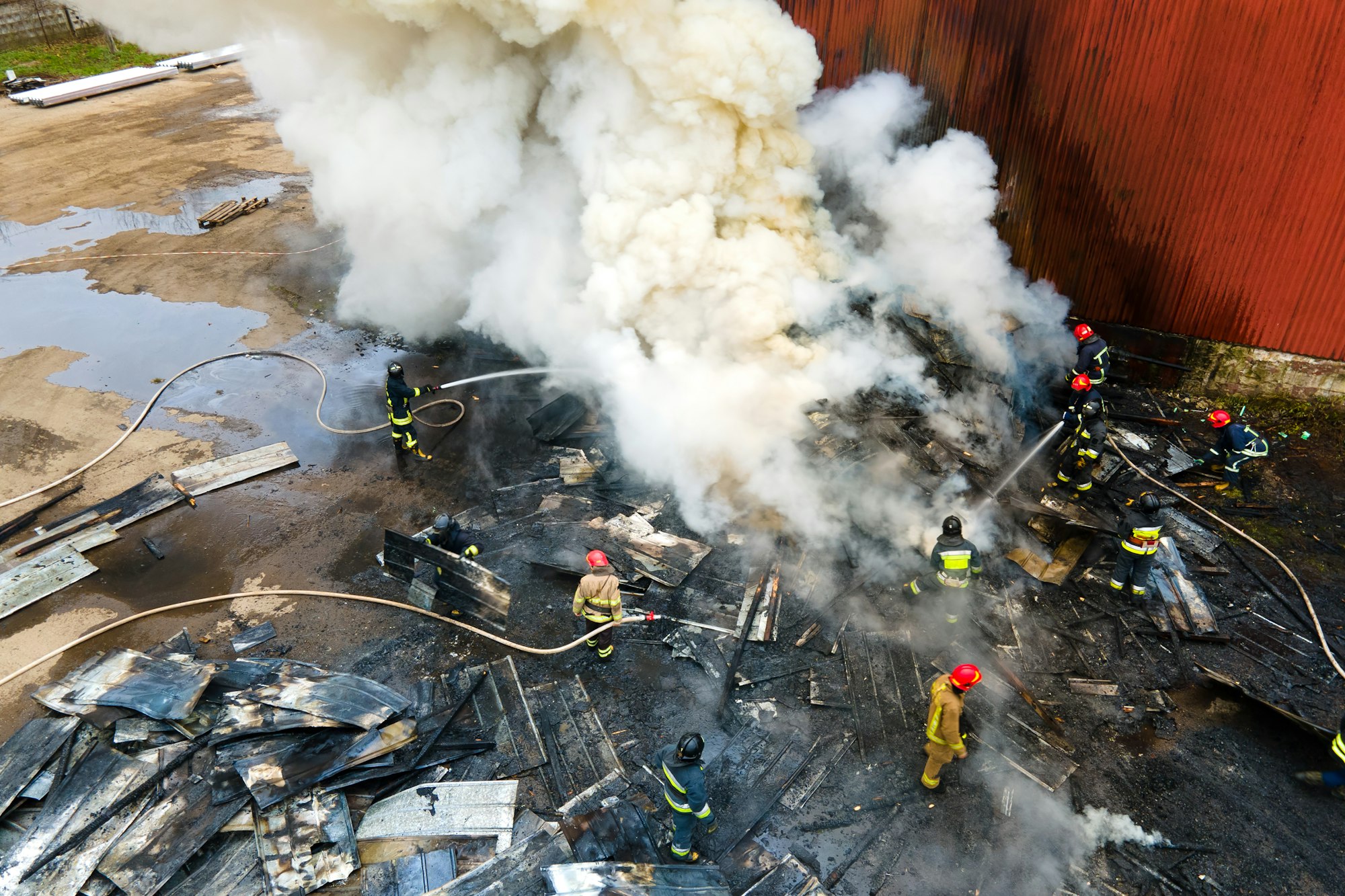 Aerial view of firefighters extinguishing fire in industrial area