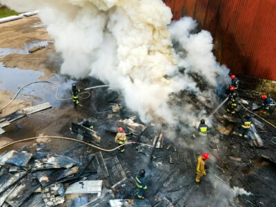 Aerial view of firefighters extinguishing fire in industrial area